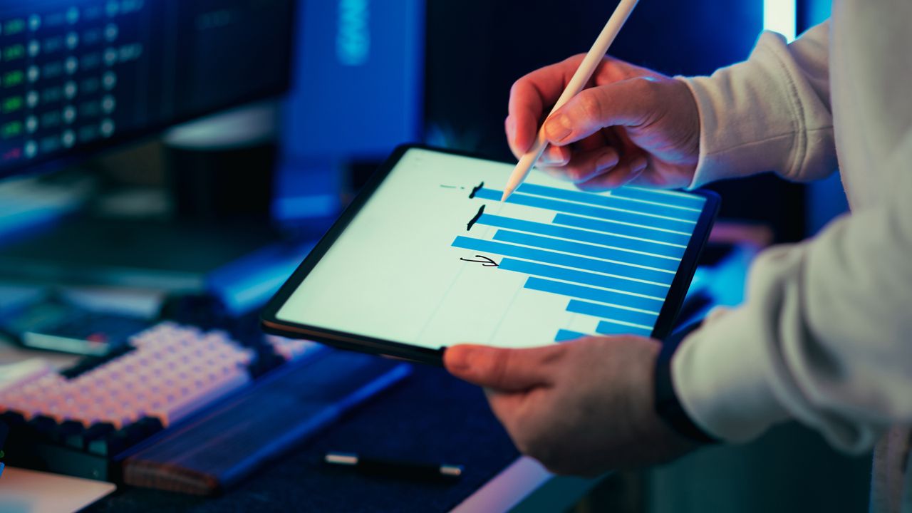 A person using a stylus on a tablet showing a business graph in an office setting.